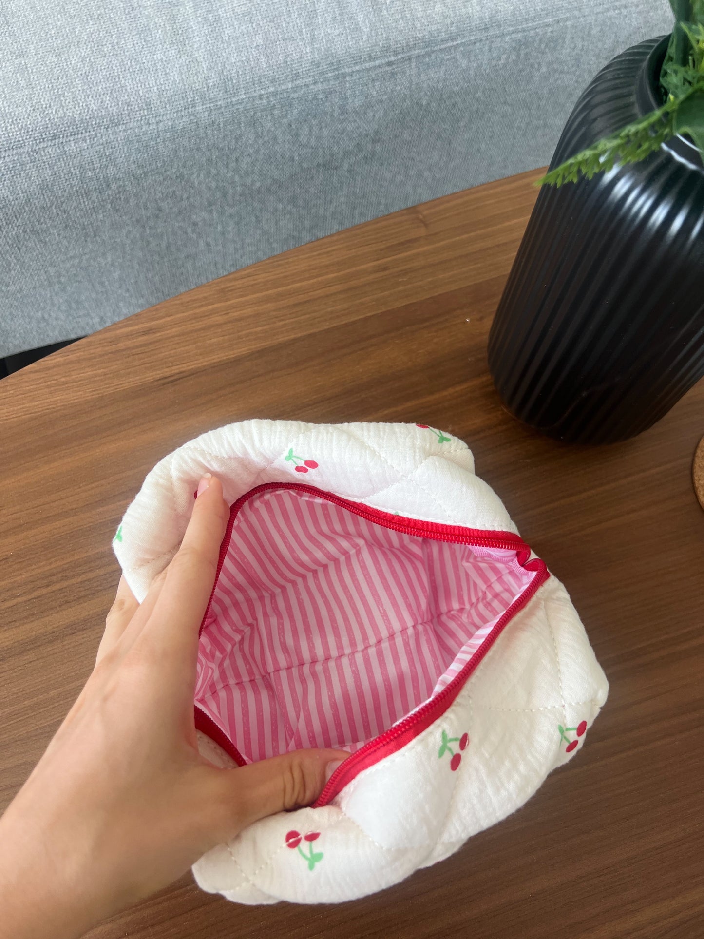 Beauty pouch with cherry designs and lined with candy pink stripes interiors. Perfect for makeup, skincare and travel.